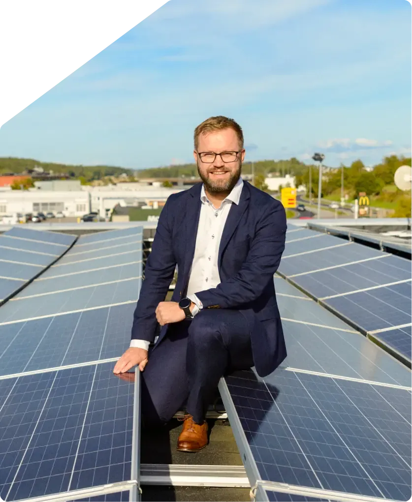 Installer sitting on a roof beside solar panels