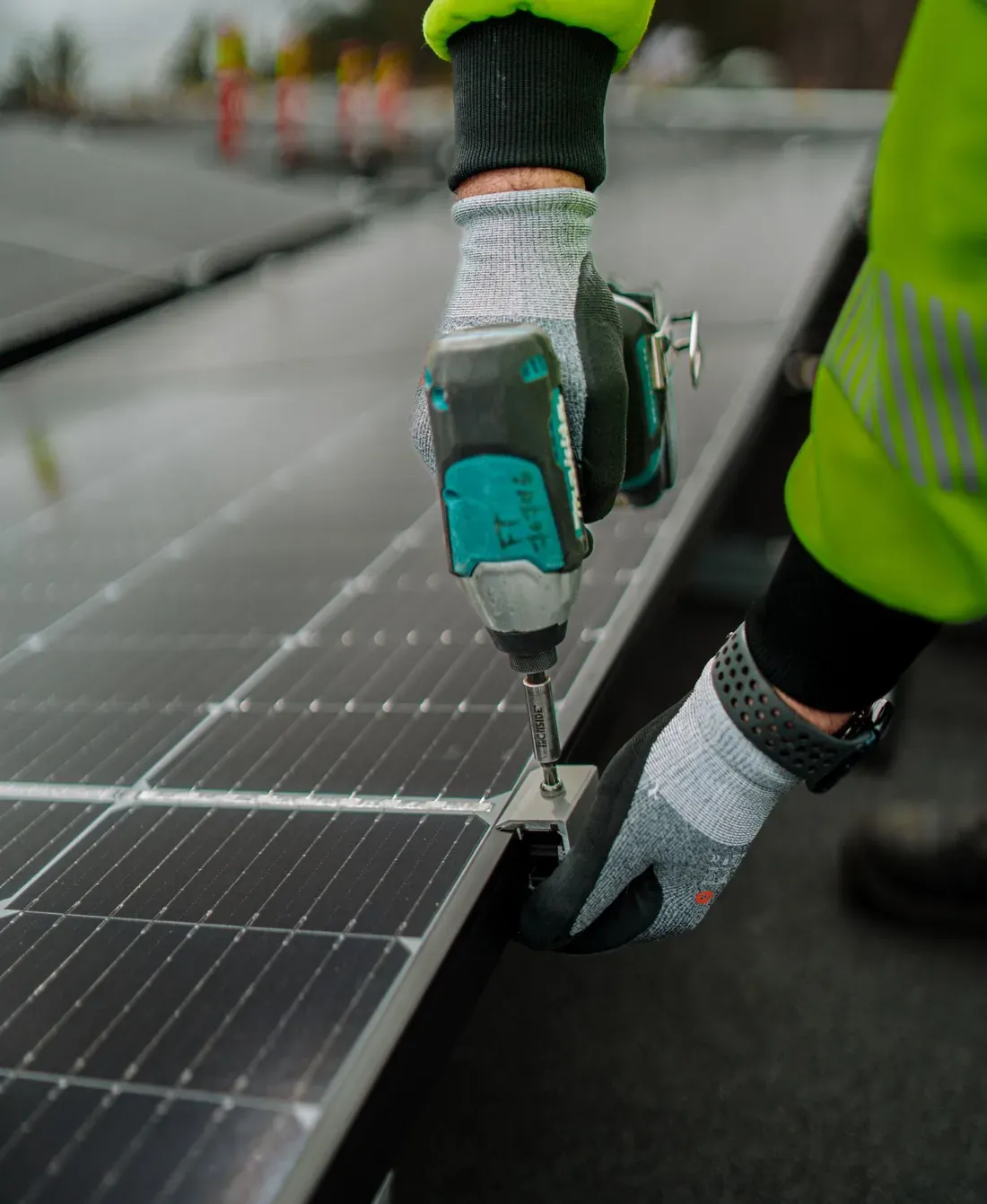 Montør i arbeidshansker fester et solcellepanel med drill